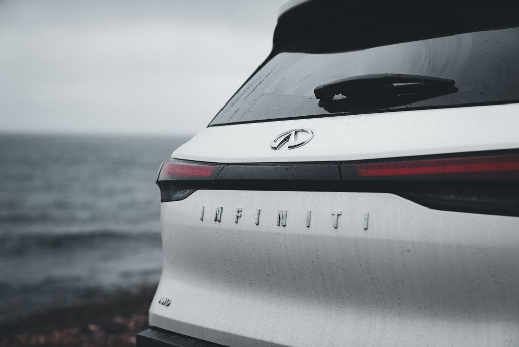 A detailed view of a car near the sea, capturing the brand logo with the ocean in the background.
