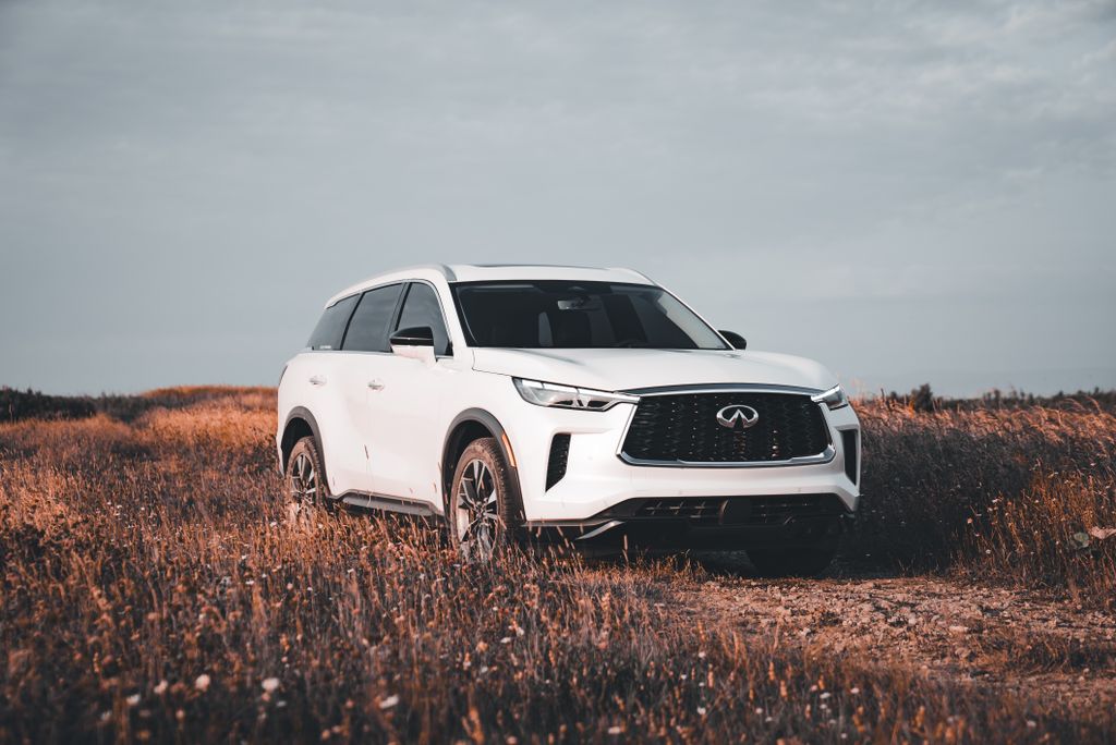 A modern white SUV parked amidst a picturesque field during sunset, offering an adventurous vibe.