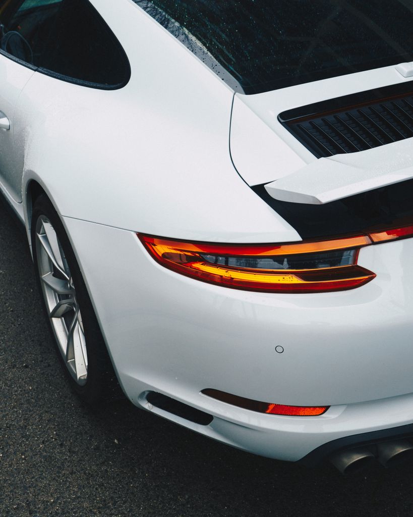 Elegant white sports car with a glossy finish parked outdoors on a rainy day.