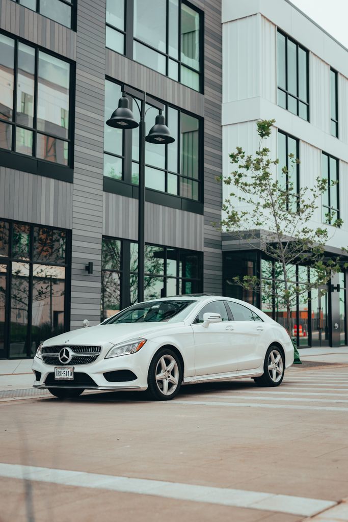 White Mercedes-Benz car parked in urban area with modern architecture and street lamps.